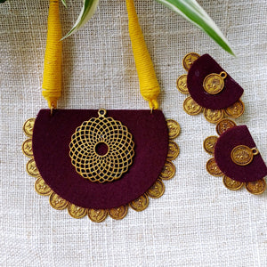 Maroon and gold necklace with matching earrings on a light fabric background
