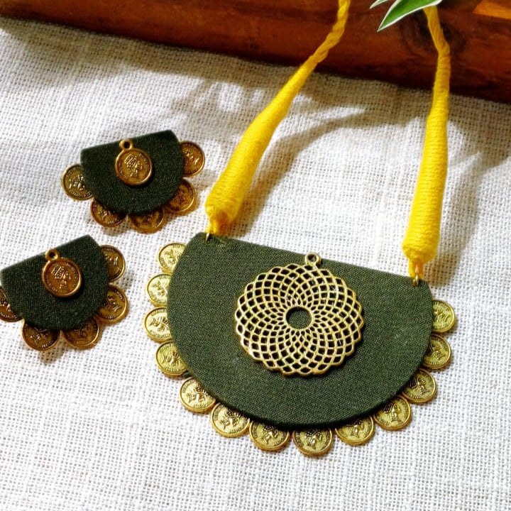 Maroon and gold necklace with matching earrings on a light fabric background